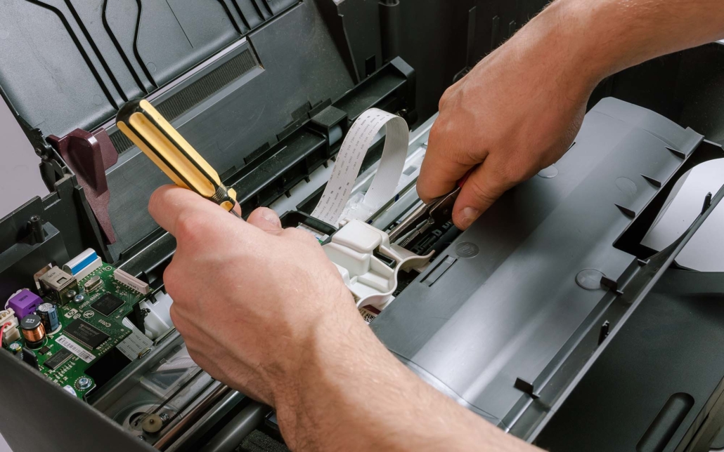 Worker's hands repairing a printer