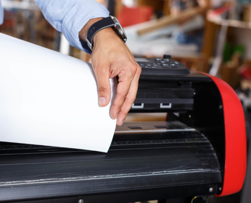 Close up view of person loading large paper sheet into wide format printer