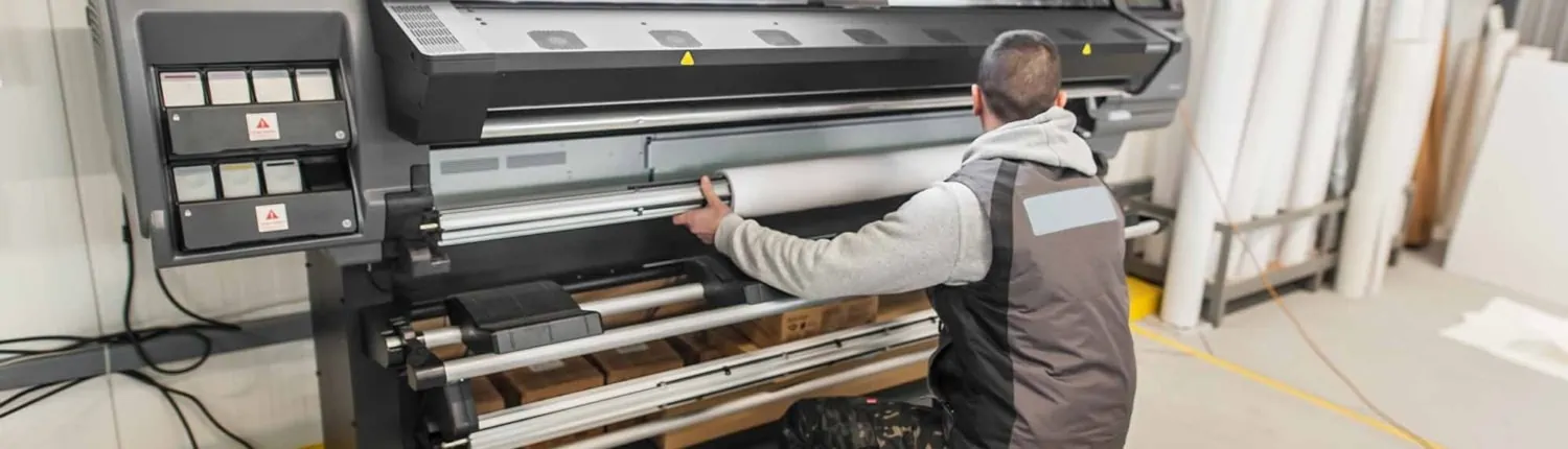 Technician operator changes paper roll on large printer plotter machine