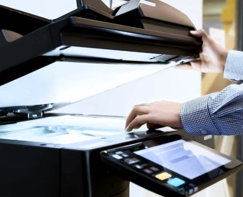 A business person's hand placing a document into the printer