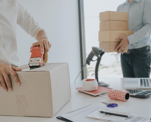 Close up of worker taping a cardboard box in office mailing room