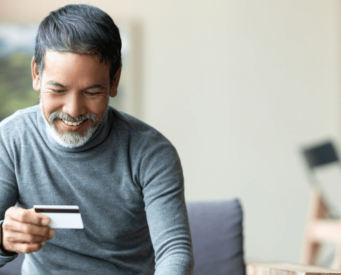 Man looking at a debit card as he buys a printer online