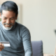 Man looking at a debit card as he buys a printer online