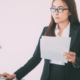 Woman holding pieces of paper as she looks at the office copier