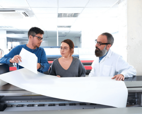 Two workers reviewing plans over a large blueprint