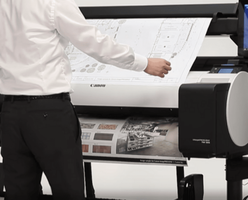 A worker reviewing documents from a CAD printer