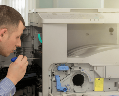 A man technician taking a close look at a broken copier