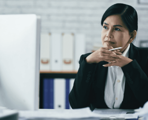 A woman lacing her fingers and looking at a computer monitor