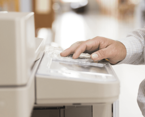 A hand pressing buttons on the office copier