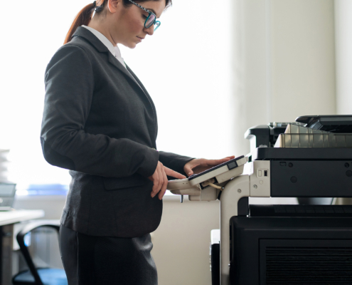 Business woman in a suit and glasses makes copies of documents on a photocopier