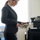 Business woman in a suit and glasses makes copies of documents on a photocopier