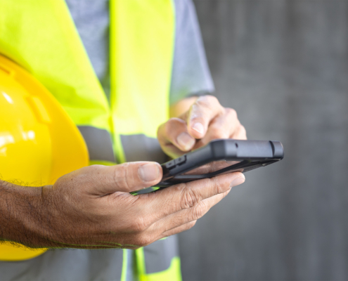 Side view, construction texting text message on smartphone