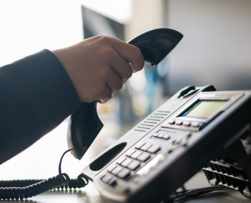 Close-up of the hand of a female office worker dialing a number on a landline phone