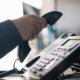 Close-up of the hand of a female office worker dialing a number on a landline phone
